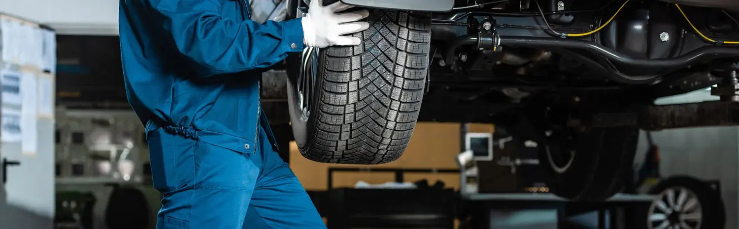 Mechaniker trägt einen Reifen von Kfz Schlegel GmbH&Co.KG